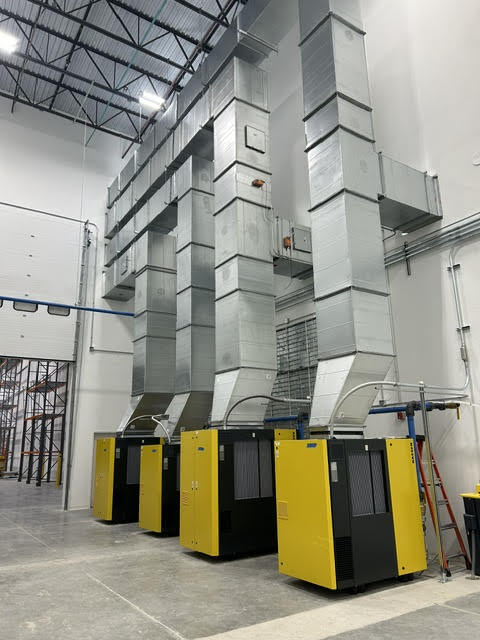 Compressed air dryers with tall overhead ducting installed in a manufacturing facility